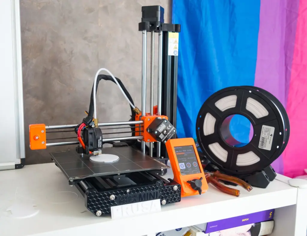 Prusa Mini 3D printer (orange) during a print