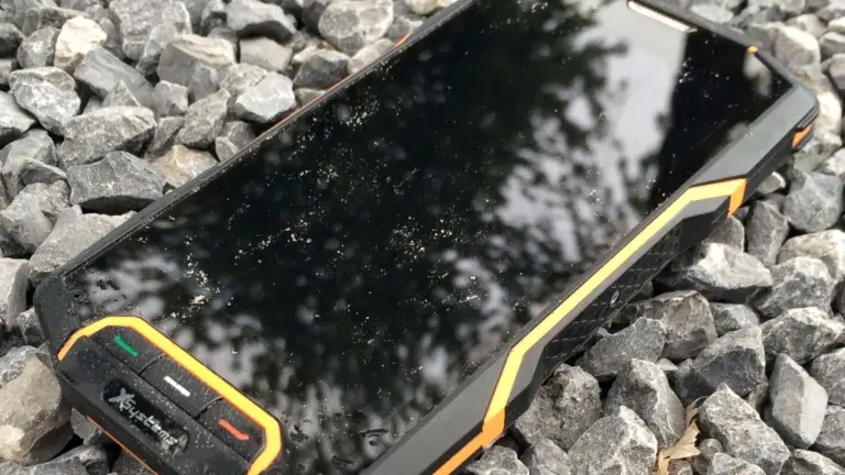 Móvil resistente al agua, mojado, apoyado sobre grava
