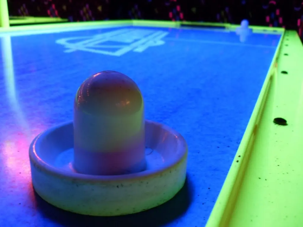 Empujador sobre una mesa de air hockey con iluminación de neón